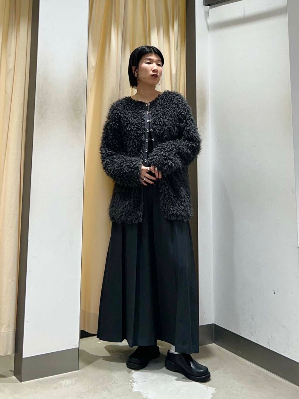 グレー系のワンピース、ブラック系のショルダーバッグ、グレー系のニット/セーターを着用したレディースの冬コーディネートの2枚目の写真