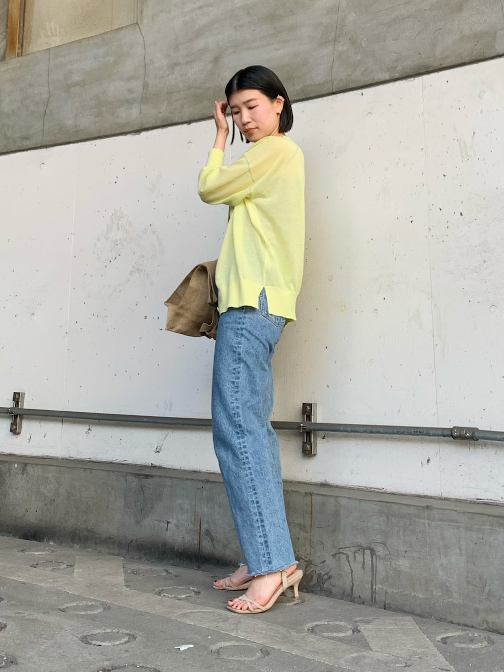 イエロー系のカーディガン/ボレロ、ブルー系のデニムパンツ、ベージュ系のキャミソールを着用したレディースの春コーディネートの2枚目の写真