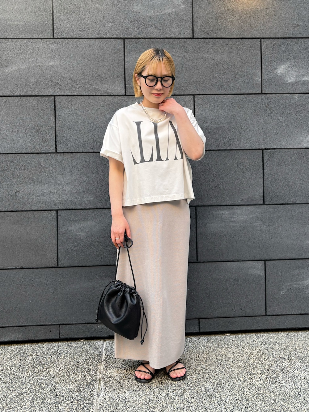 ブラック系のショルダーバッグ、グレー系のスカート、ホワイト系のTシャツ/カットソーを着用したレディースの春コーディネートの3枚目の写真