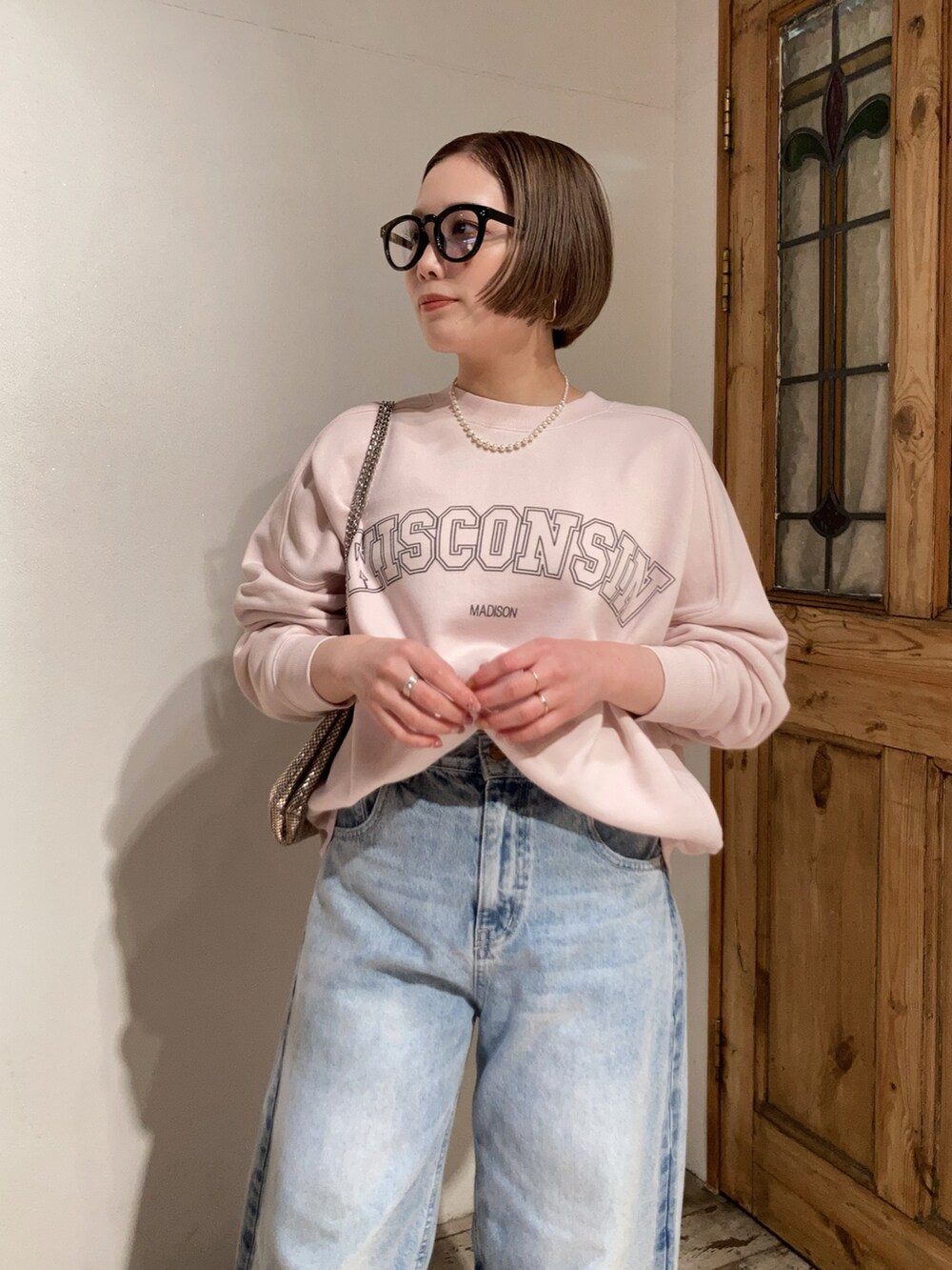 ブルー系のデニムパンツ、ピンク系のスウェット、ゴールド系のショルダーバッグを着用したレディースの冬コーディネートの4枚目の写真