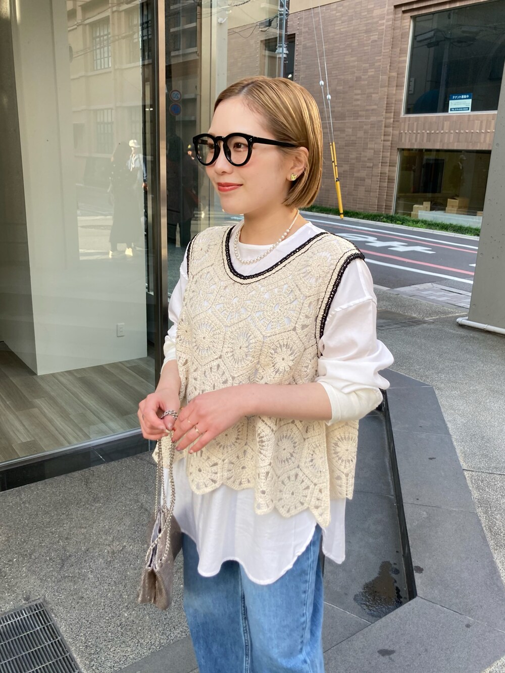 ゴールド系のショルダーバッグ、ブルー系のデニムパンツ、その他のトップスを着用したレディースの春コーディネートの4枚目の写真