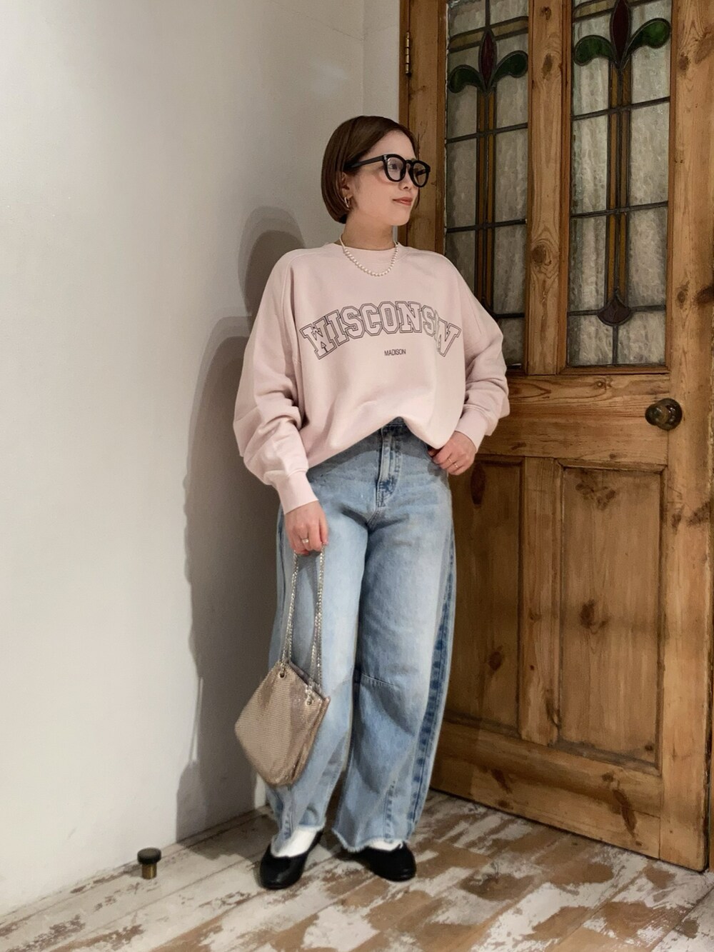 ブルー系のデニムパンツ、ピンク系のスウェット、ゴールド系のショルダーバッグを着用したレディースの冬コーディネートの2枚目の写真