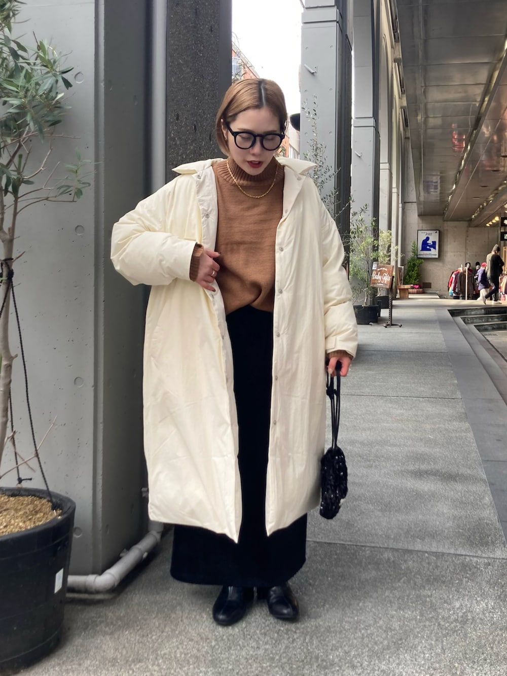 ベージュ系のニット/セーター、ホワイト系のダウンジャケット/コート、ブラック系のスカートを着用したレディースの冬コーディネートの2枚目の写真