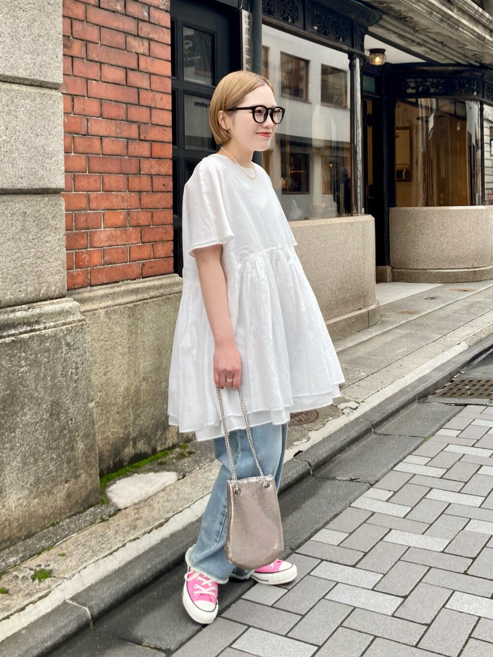 ブルー系のデニムパンツ、ゴールド系のショルダーバッグ、ブルー系のデニムパンツを着用したレディースの春コーディネートの3枚目の写真