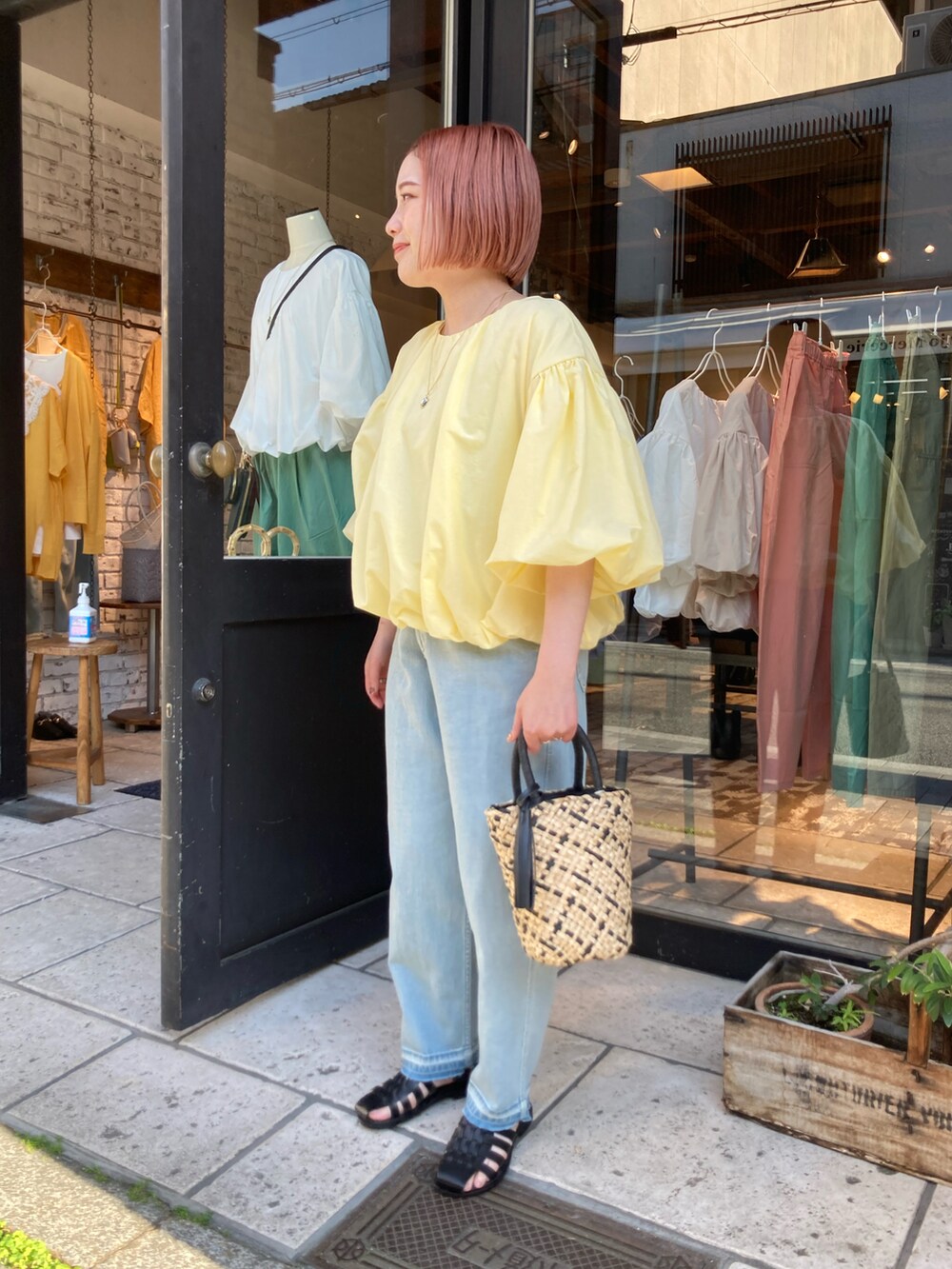 イエロー系のTシャツ/カットソー、ブルー系のデニムパンツ、ベージュ系のハンドバッグを着用したレディースの夏コーディネートの4枚目の写真