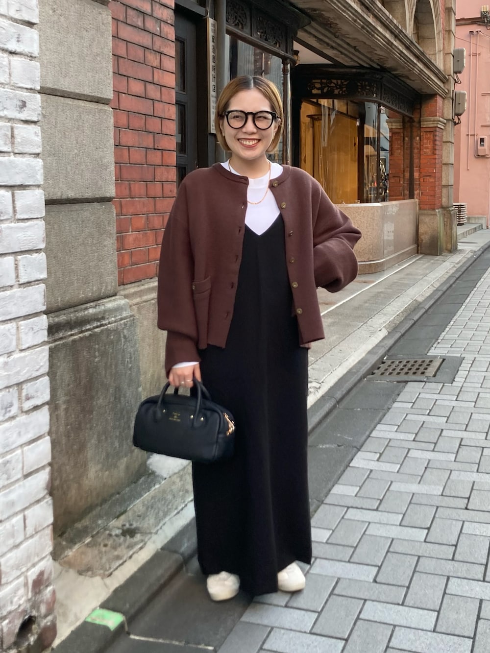 ブラック系のショルダーバッグ、ブラウン系のカーディガン/ボレロ、ブラック系のワンピースを着用したレディースの秋コーディネートの2枚目の写真