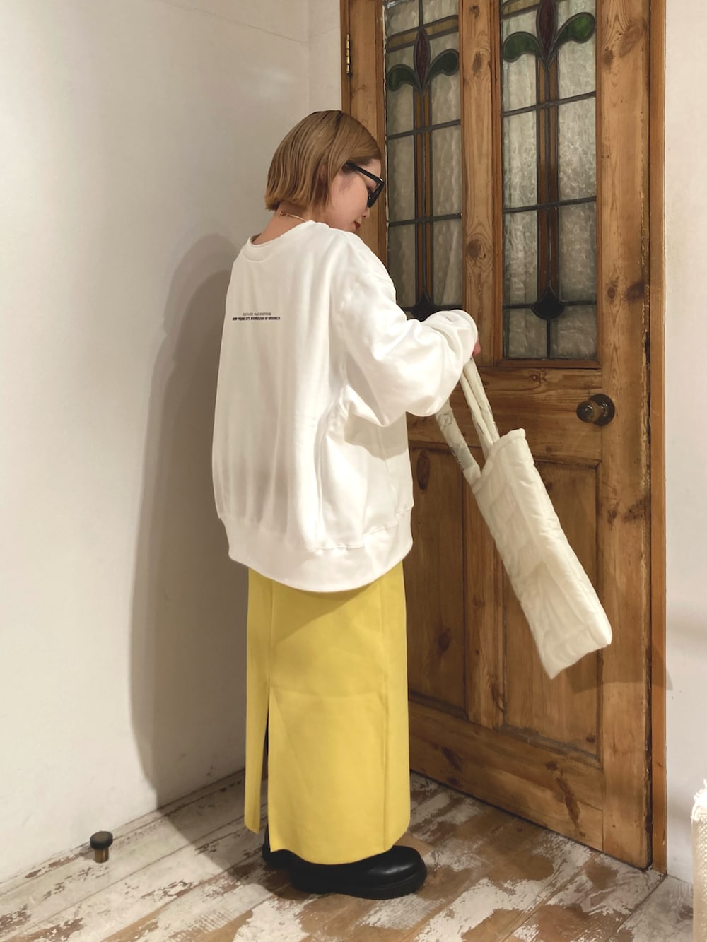 ブラック系のブーツ、イエロー系のスカート、ホワイト系のスウェットを着用したレディースの冬コーディネートの2枚目の写真