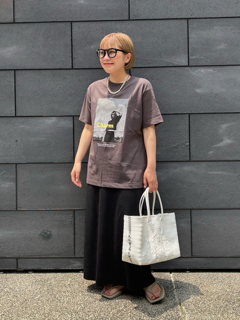 ブラック系のスカート、ベージュ系のサンダル、グレー系のTシャツ/カットソーを着用したレディースの夏コーディネートの3枚目の写真