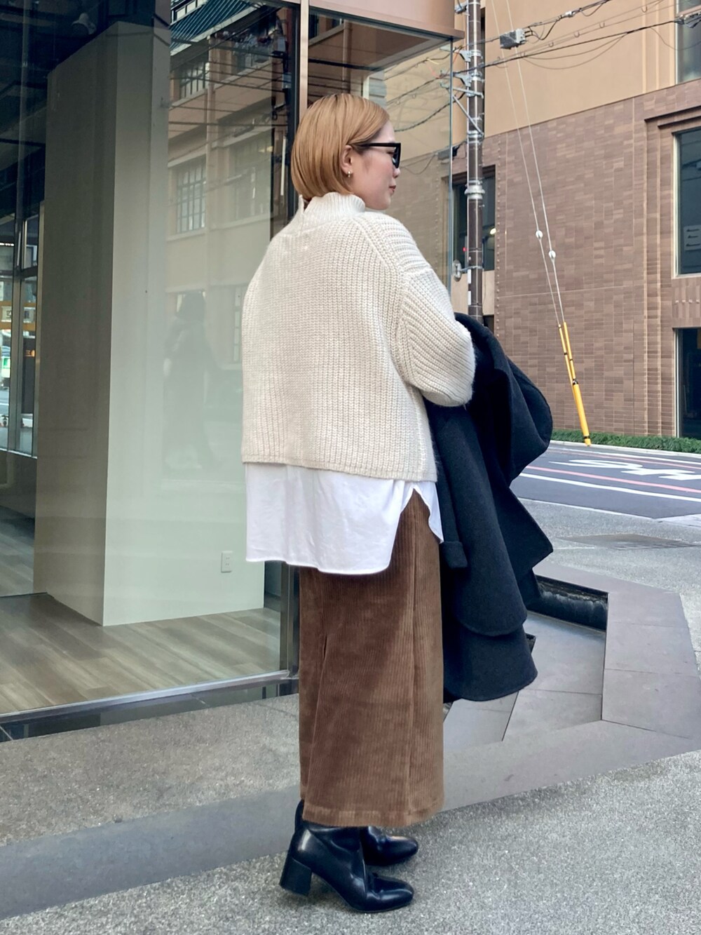 ブラック系のブーツ、ゴールド系のショルダーバッグ、ブラウン系のスカートを着用したレディースの冬コーディネートの4枚目の写真