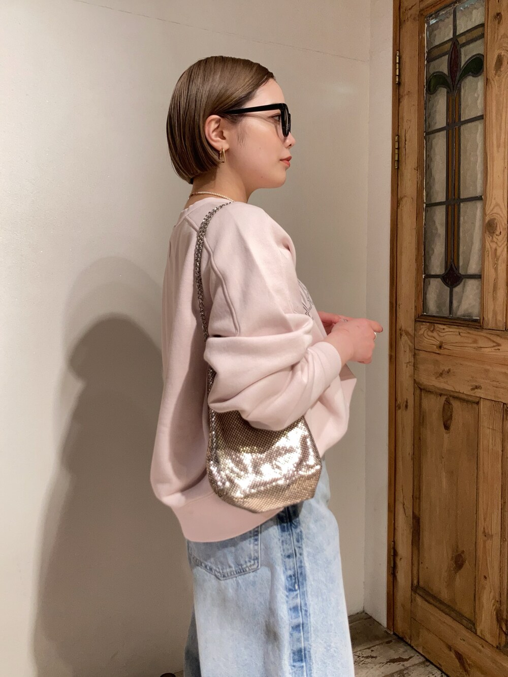 ブルー系のデニムパンツ、ピンク系のスウェット、ゴールド系のショルダーバッグを着用したレディースの冬コーディネートの5枚目の写真
