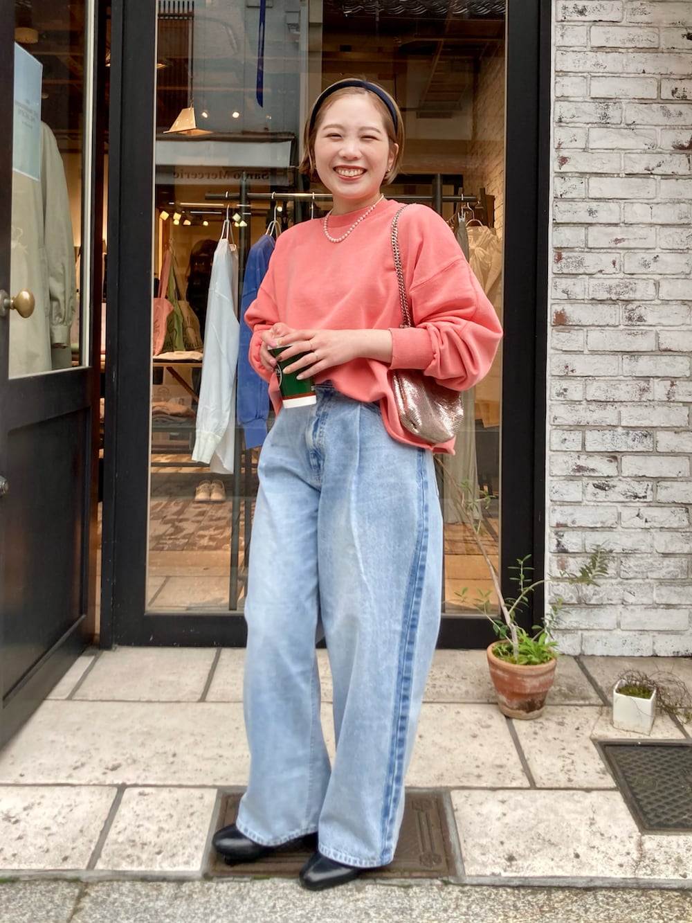 ブラック系のブーツ、ブルー系のデニムパンツ、オレンジ系のスウェットを着用したレディースの冬コーディネートの5枚目の写真