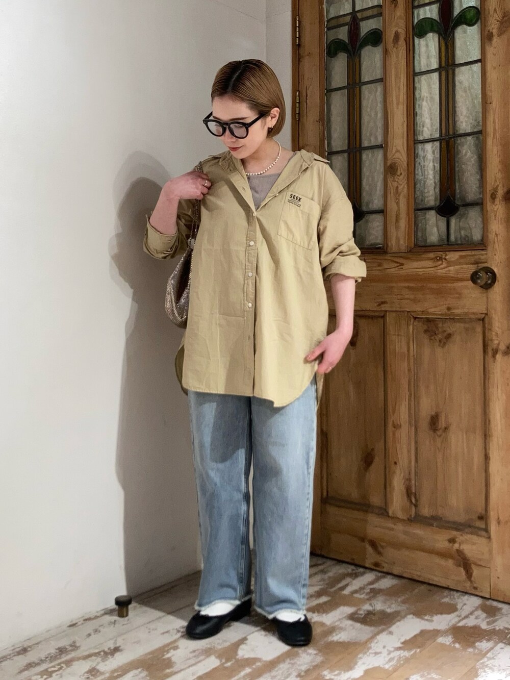 ゴールド系のショルダーバッグ、ブルー系のデニムパンツ、イエロー系のシャツ/ブラウスを着用したレディースの春コーディネートの2枚目の写真