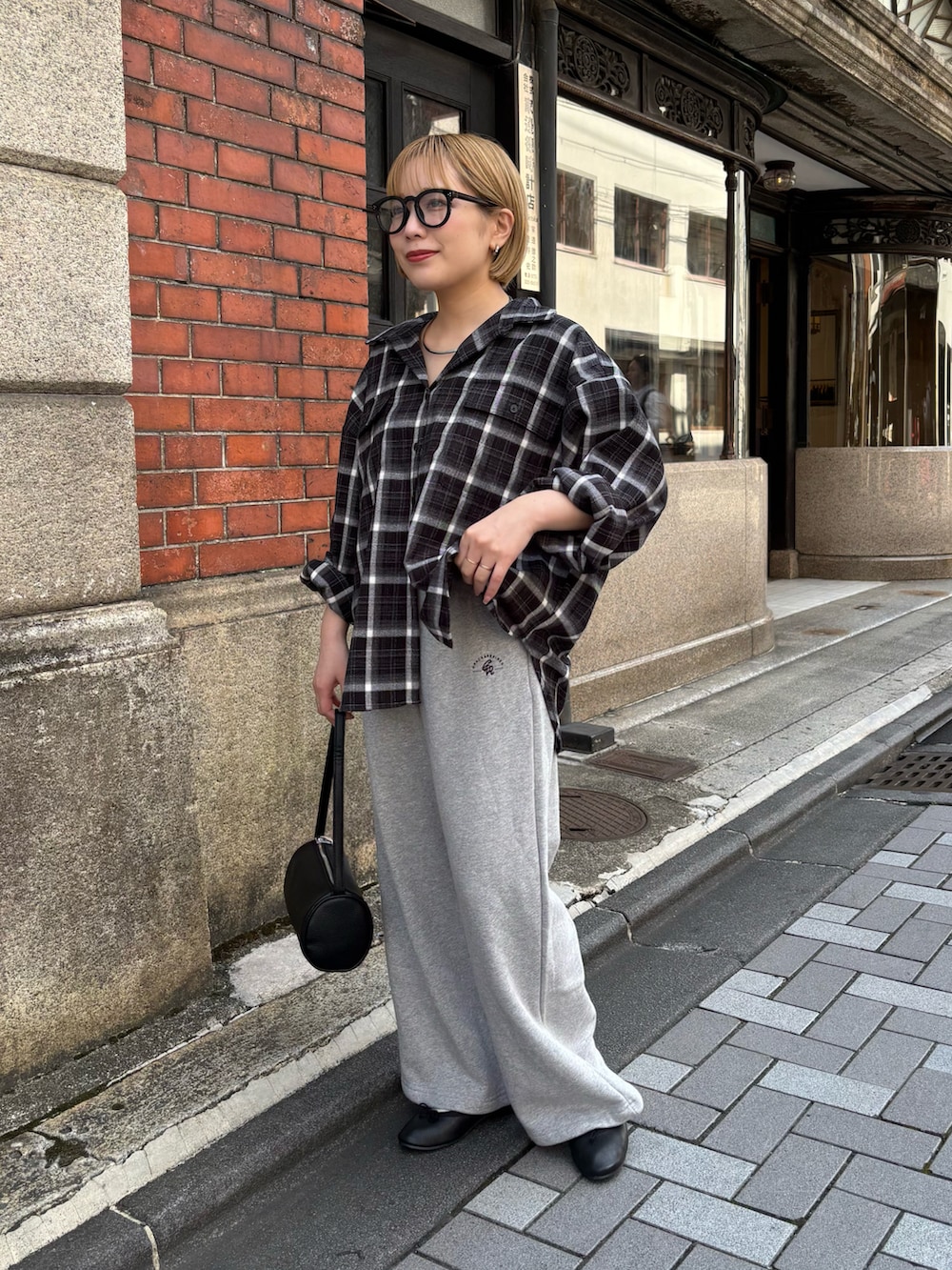 ブラック系のハンドバッグ、グレー系のスウェットパンツ、ブラック系のシャツ/ブラウスを着用したレディースの秋コーディネートの2枚目の写真