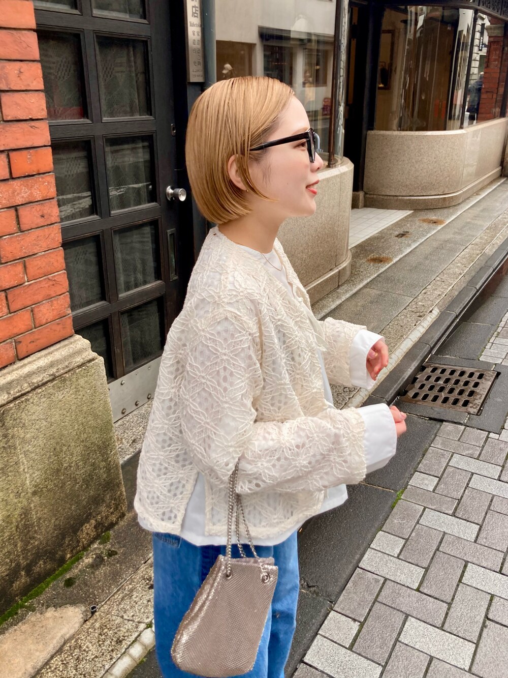 ブルー系のデニムパンツ、ゴールド系のショルダーバッグ、ホワイト系のシャツ/ブラウスを着用したレディースの春コーディネートの4枚目の写真