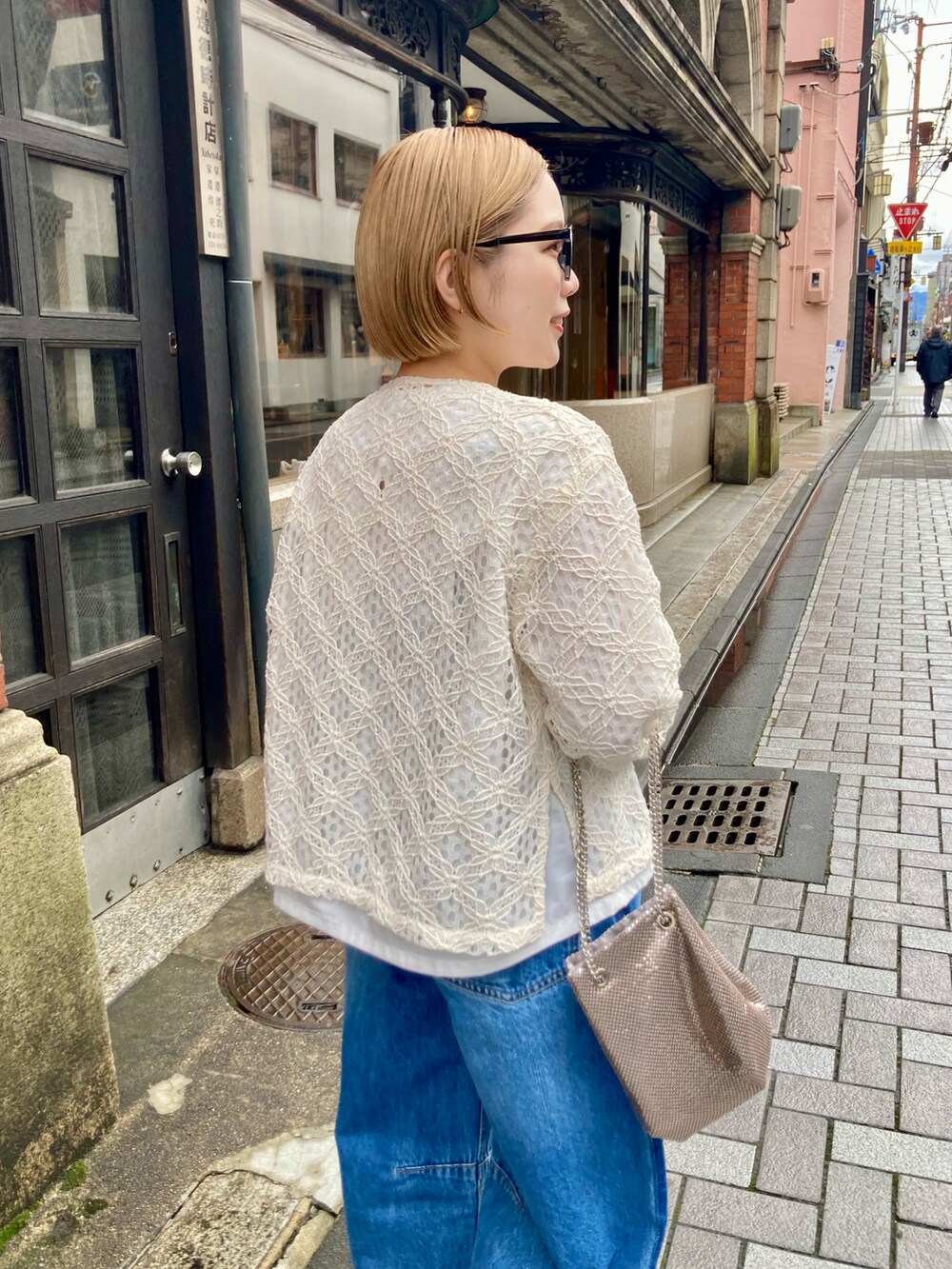 ブルー系のデニムパンツ、ゴールド系のショルダーバッグ、ホワイト系のシャツ/ブラウスを着用したレディースの春コーディネートの5枚目の写真