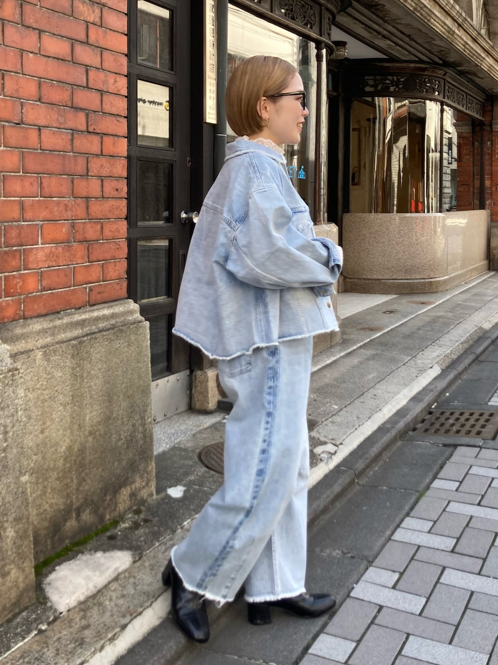 ブラック系のブーツ、ゴールド系のショルダーバッグ、ブルー系のデニムパンツを着用したレディースの冬コーディネートの3枚目の写真