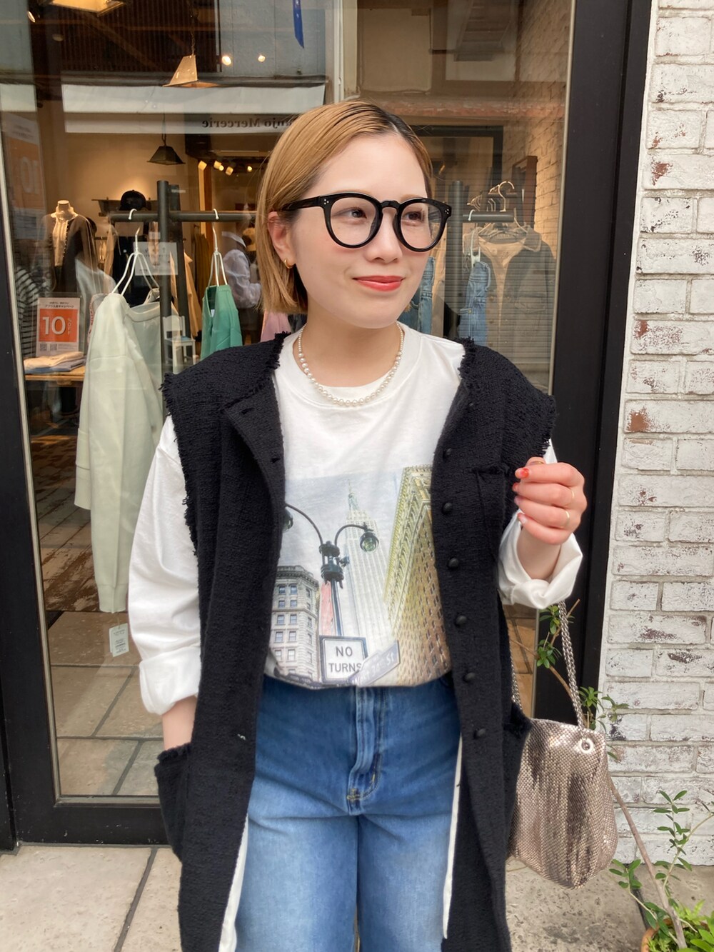 ブルー系のデニムパンツ、ホワイト系のTシャツ/カットソー、ブラック系のベストを着用したレディースの春コーディネートの4枚目の写真