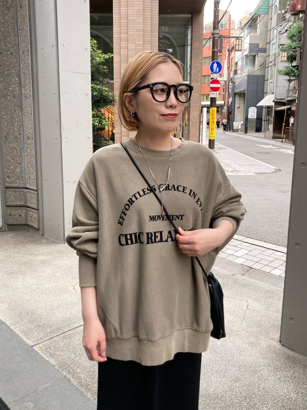 ブラック系のスカート、ベージュ系のスウェット、ブラック系のショルダーバッグを着用したレディースの秋コーディネートの5枚目の写真