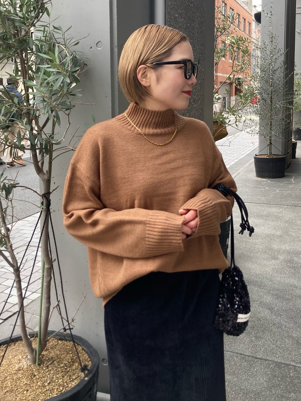 ブラック系のスカート、ベージュ系のニット/セーター、ブラック系のショルダーバッグを着用したレディースの冬コーディネートの4枚目の写真