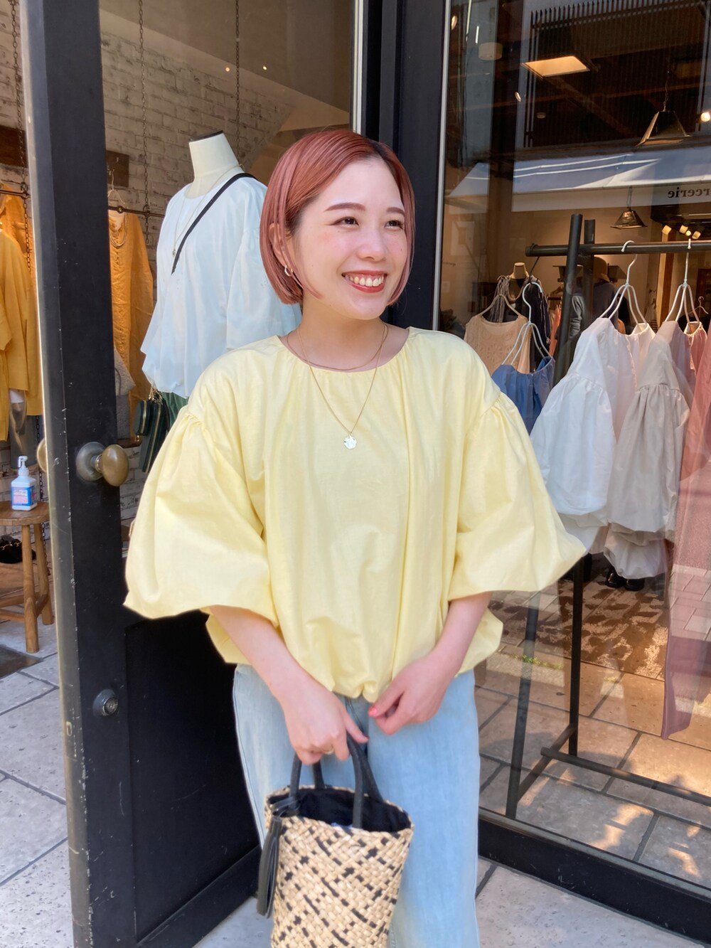 イエロー系のTシャツ/カットソー、ブルー系のデニムパンツ、ベージュ系のハンドバッグを着用したレディースの夏コーディネートの5枚目の写真