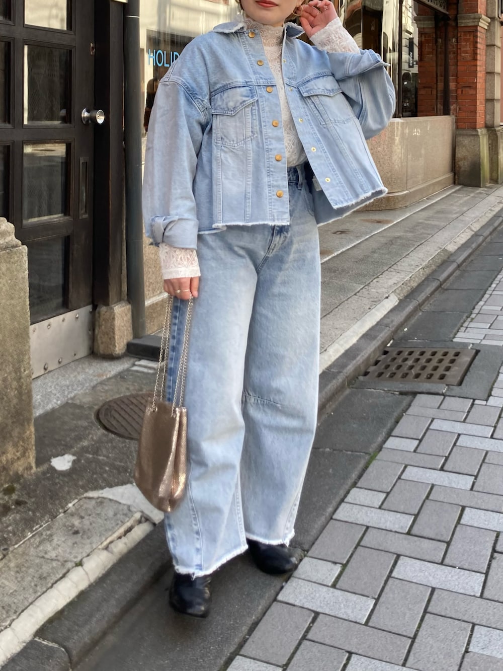 ブラック系のブーツ、ゴールド系のショルダーバッグ、ブルー系のデニムパンツを着用したレディースの冬コーディネートの4枚目の写真