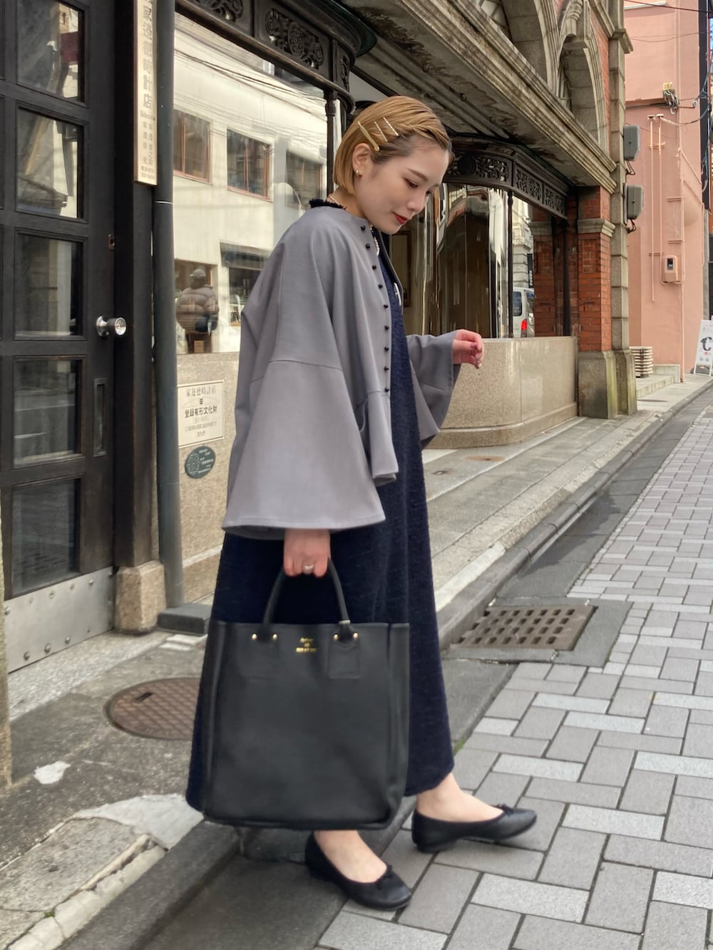 ブラック系のトートバッグ、ブルー系のワンピース、グレー系のノーカラージャケットを着用したレディースの冬コーディネートの3枚目の写真