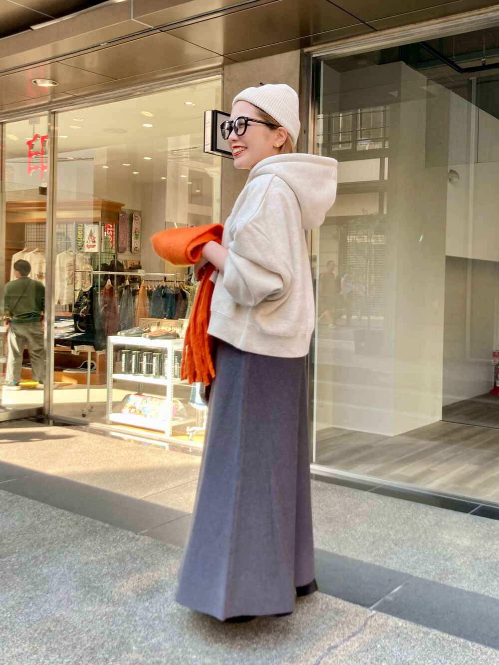 ブラック系のブーツ、グレー系のスカート、ゴールド系のショルダーバッグを着用したレディースの秋コーディネートの2枚目の写真