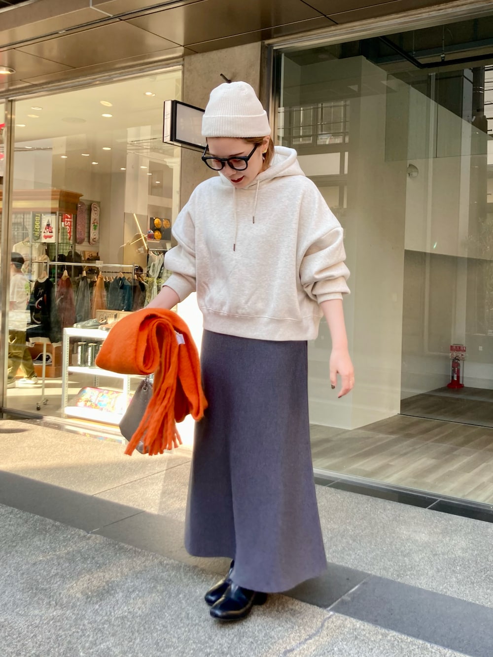 ブラック系のブーツ、グレー系のスカート、ゴールド系のショルダーバッグを着用したレディースの秋コーディネートの3枚目の写真