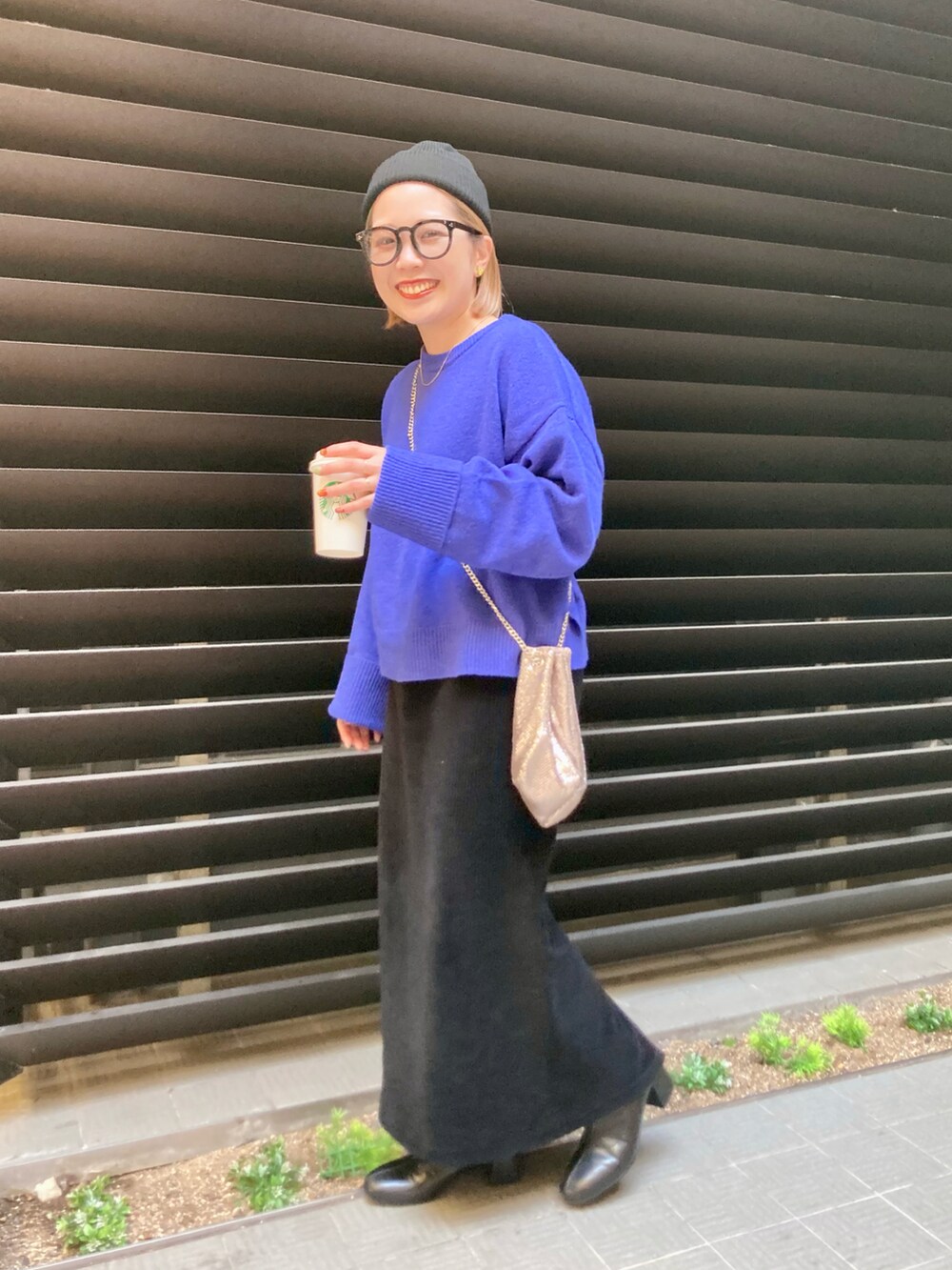 ブルー系のニット/セーター、ブラック系のスカート、ゴールド系のショルダーバッグを着用したレディースの秋コーディネートの3枚目の写真