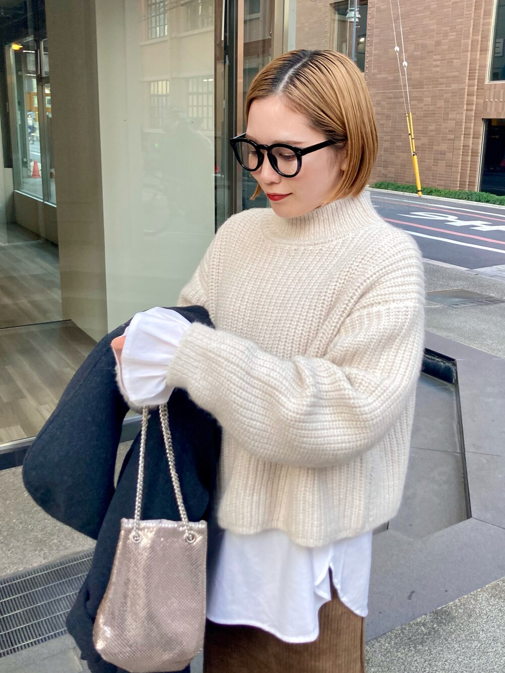 ブラック系のブーツ、ゴールド系のショルダーバッグ、ブラウン系のスカートを着用したレディースの冬コーディネートの5枚目の写真