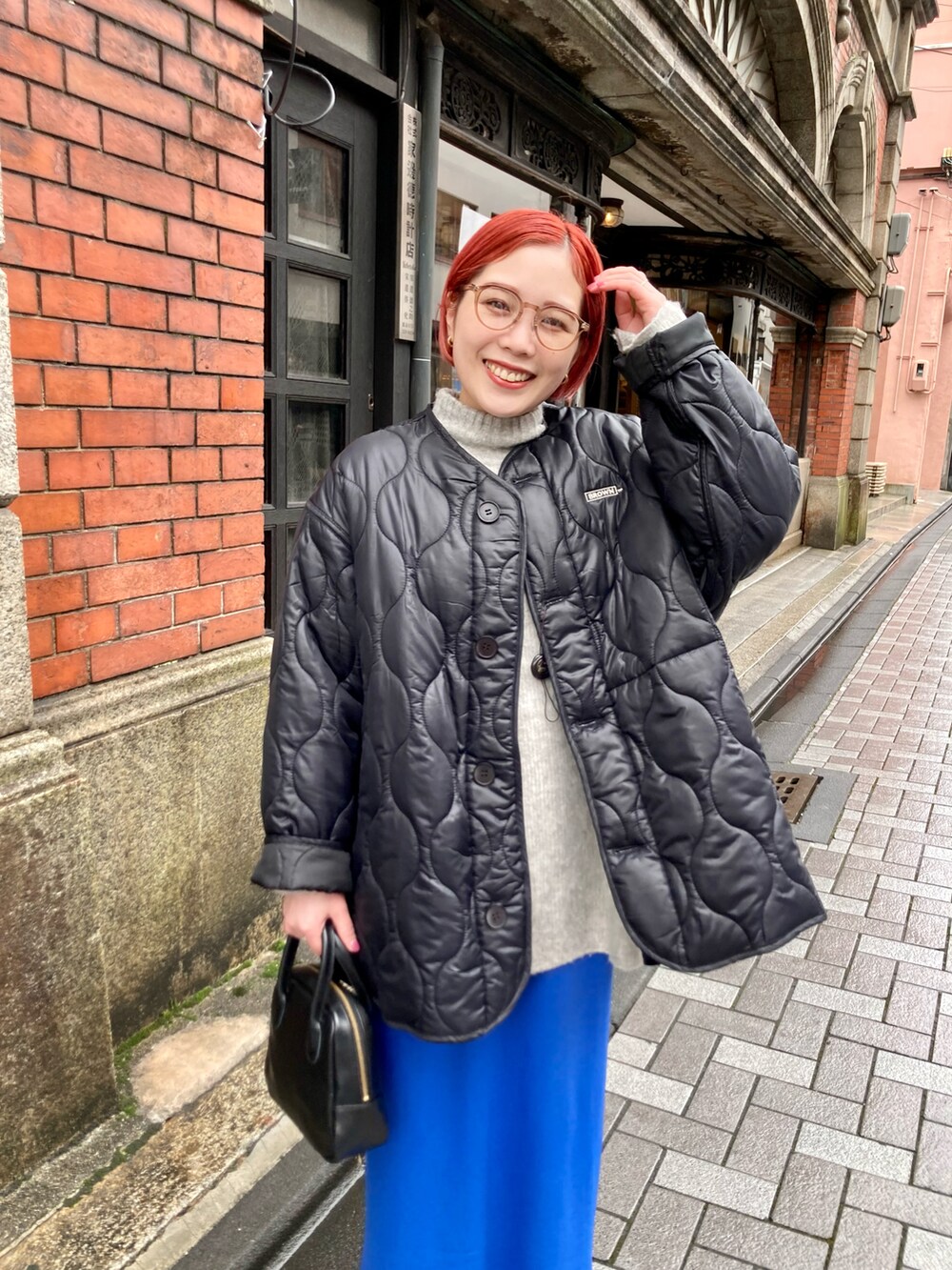 ブルー系のスカート、ブラック系のその他アウター、ベージュ系のニット/セーターを着用したレディースの冬コーディネートの4枚目の写真