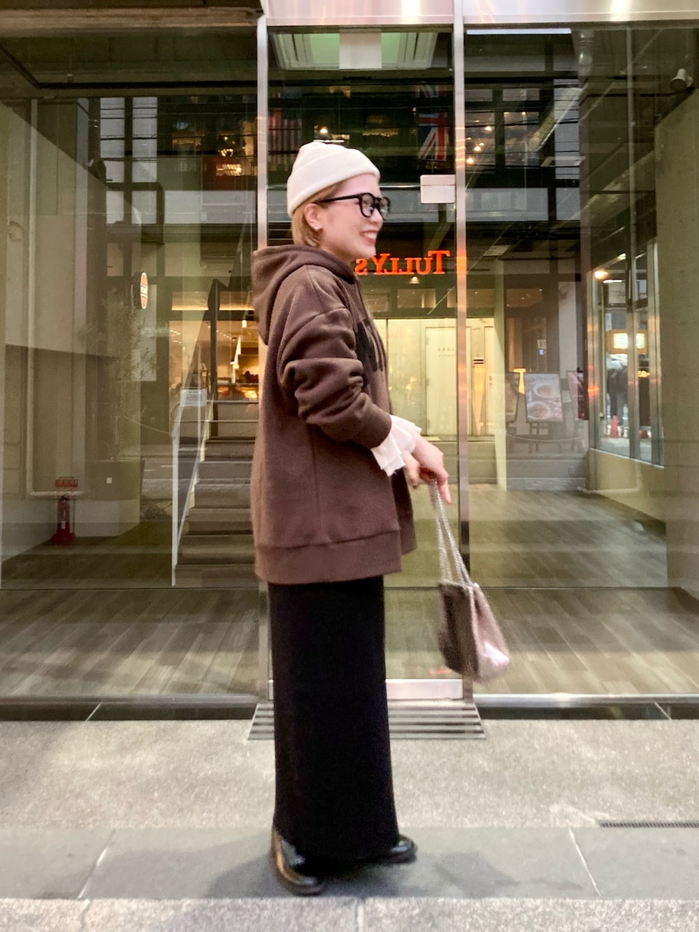 ブラウン系のパーカー、ブラック系のスカート、ゴールド系のショルダーバッグを着用したレディースの秋コーディネートの3枚目の写真