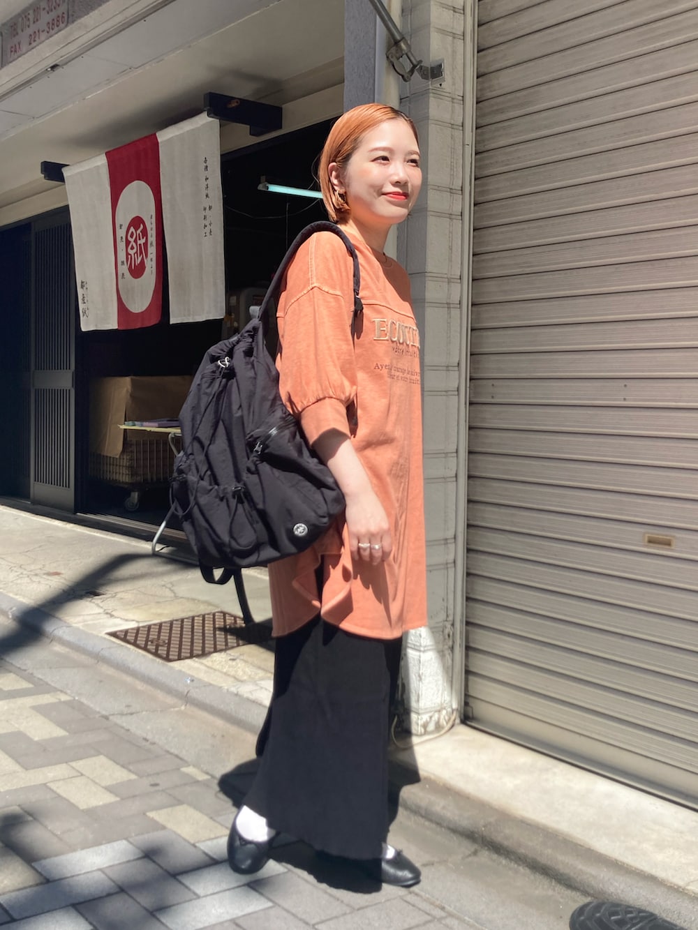 ブラック系のスカート、オレンジ系のTシャツ/カットソー、オレンジ系のTシャツ/カットソーを着用したレディースの秋コーディネートの3枚目の写真