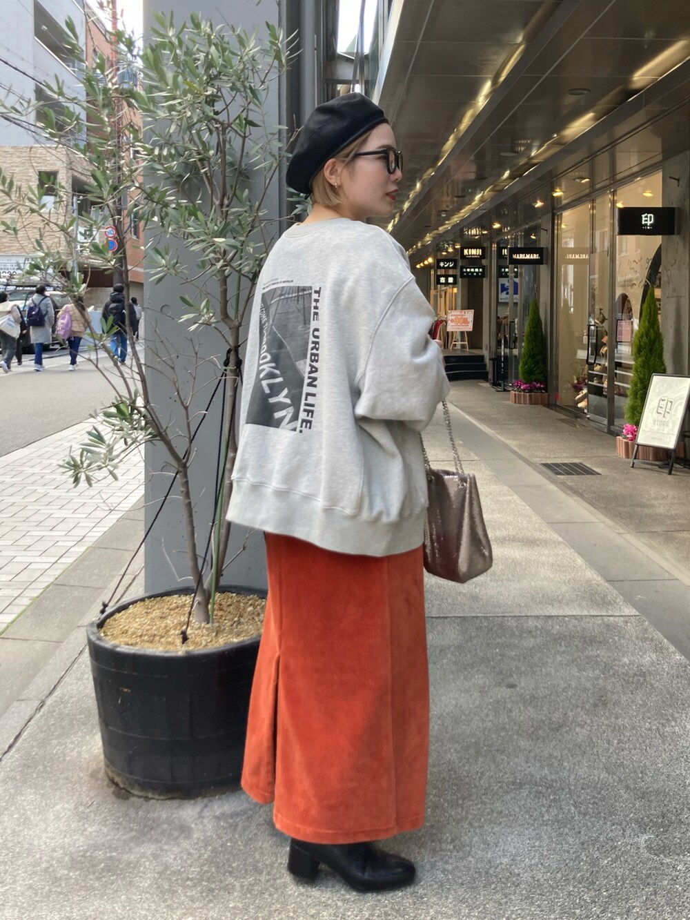 ブラック系のブーツ、オレンジ系のスカート、オレンジ系のスカートを着用したレディースの冬コーディネートの2枚目の写真