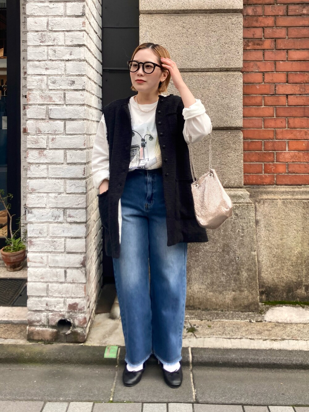 ブルー系のデニムパンツ、ホワイト系のTシャツ/カットソー、ブラック系のベストを着用したレディースの春コーディネートの2枚目の写真