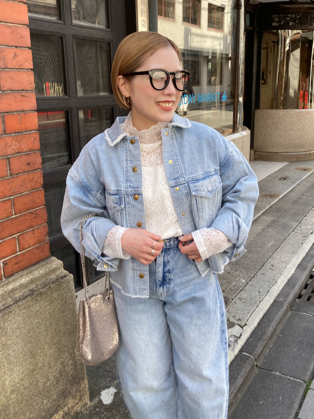 ブラック系のブーツ、ゴールド系のショルダーバッグ、ブルー系のデニムパンツを着用したレディースの冬コーディネートの5枚目の写真