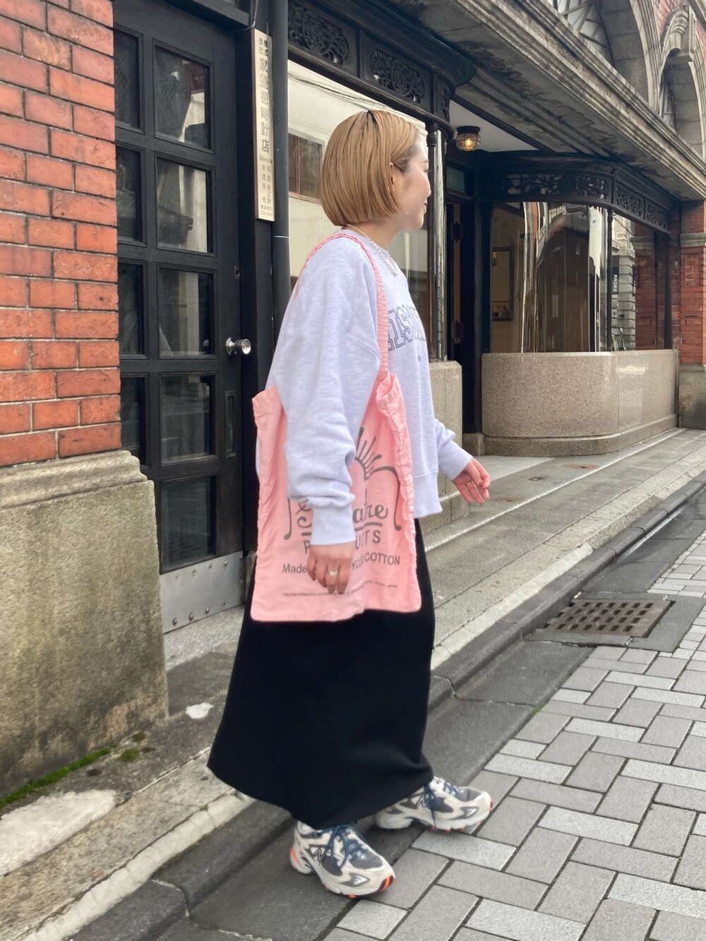 グレー系のスニーカー、ブラック系のスカート、ピンク系のバッグを着用したレディースの冬コーディネートの3枚目の写真