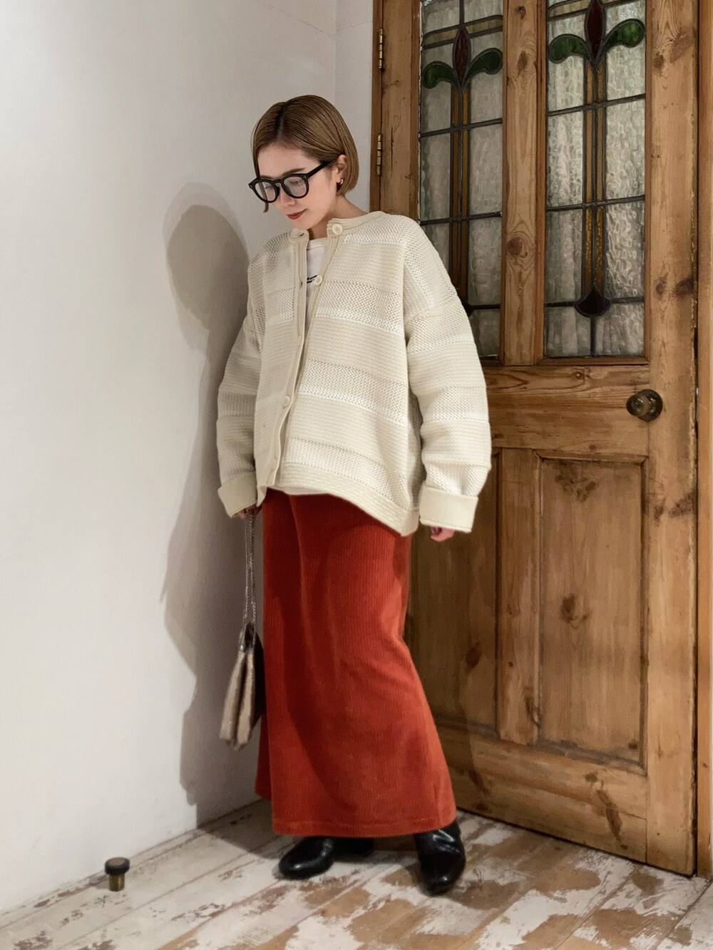 ブラック系のブーツ、ゴールド系のショルダーバッグ、オレンジ系のスカートを着用したレディースの冬コーディネートの3枚目の写真