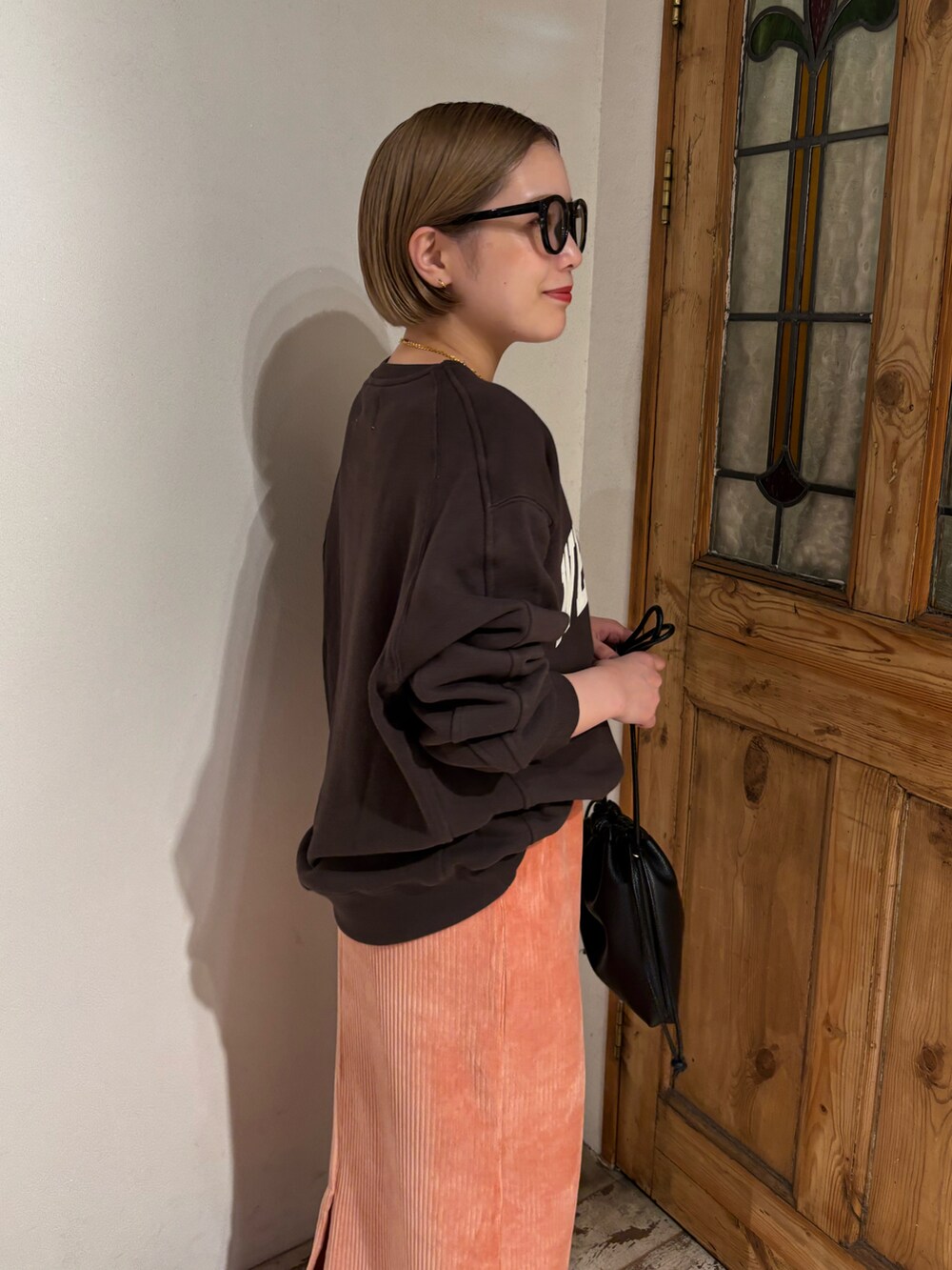 ピンク系のスカート、ブラック系のショルダーバッグ、ブラック系のブーツを着用したレディースの秋コーディネートの5枚目の写真