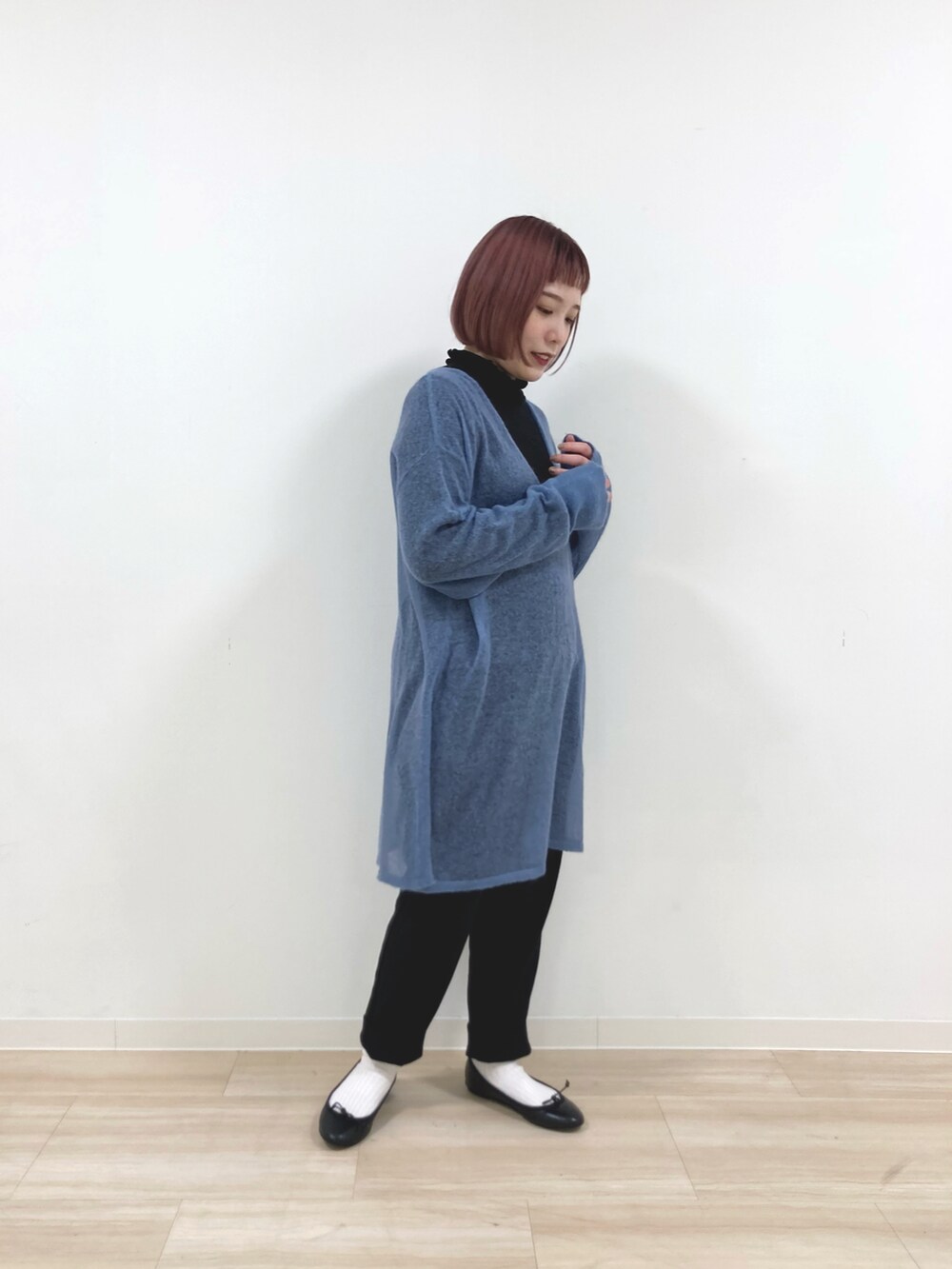 ブラック系のノーカラーコート、ブラック系のTシャツ/カットソー、ブルー系のニット/セーターを着用したレディースの冬コーディネートの3枚目の写真