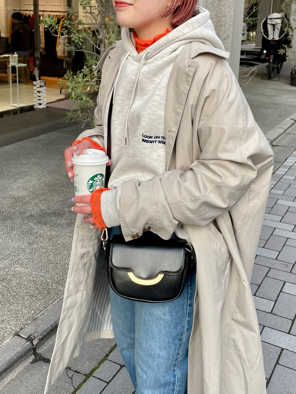 グレー系のパーカー、ブルー系のデニムパンツ、ブラック系のショルダーバッグを着用したレディースの冬コーディネートの3枚目の写真
