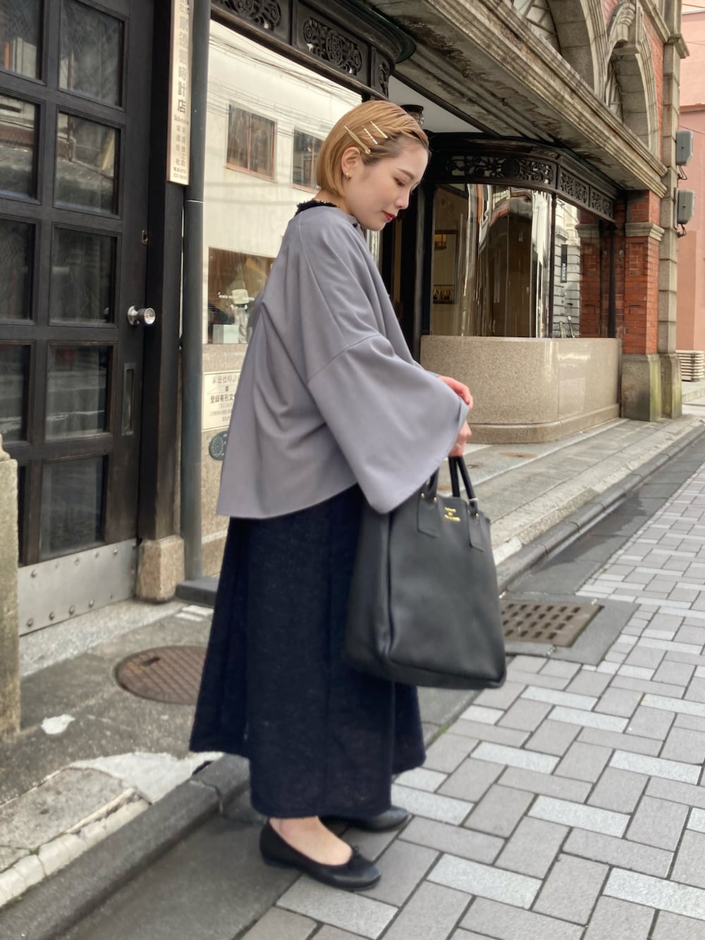 ブラック系のトートバッグ、ブルー系のワンピース、グレー系のノーカラージャケットを着用したレディースの冬コーディネートの2枚目の写真