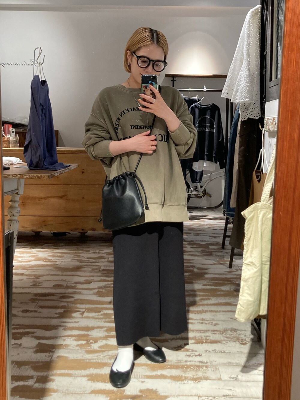 ブラック系のスカート、ベージュ系のスウェット、ブラック系のショルダーバッグを着用したレディースの秋コーディネートの4枚目の写真