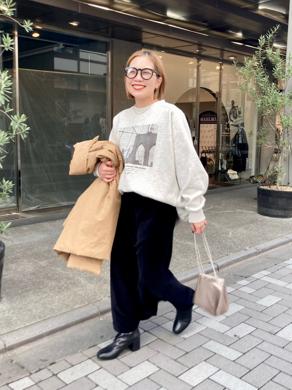 ベージュ系のダウンジャケット/コート、ベージュ系のスウェット、ゴールド系のショルダーバッグを着用したレディースの秋コーディネートの2枚目の写真