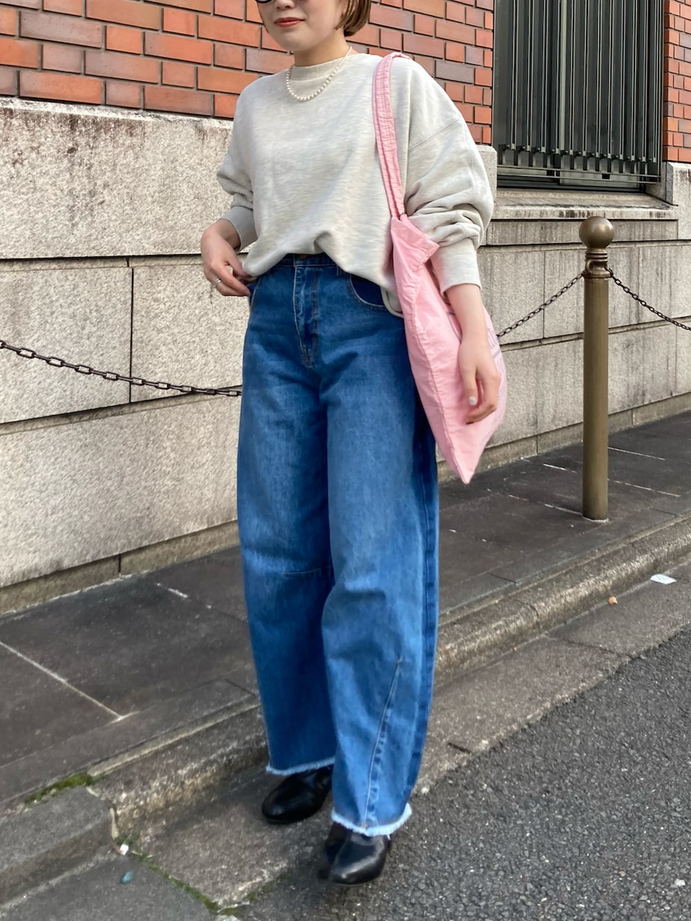 ブラック系のブーツ、ブルー系のデニムパンツ、ピンク系のバッグを着用したレディースの冬コーディネートの3枚目の写真