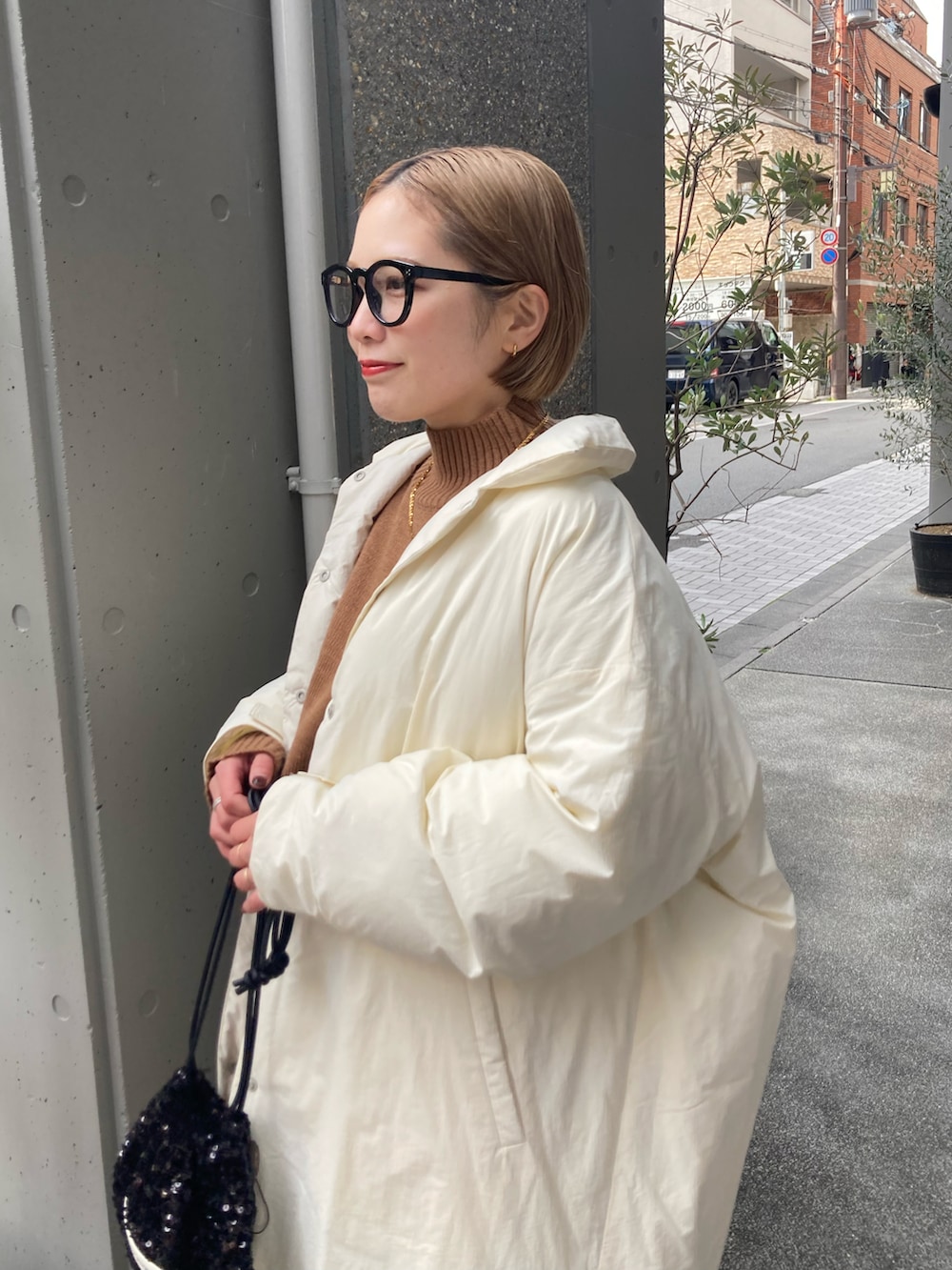 ベージュ系のニット/セーター、ホワイト系のダウンジャケット/コート、ブラック系のスカートを着用したレディースの冬コーディネートの5枚目の写真