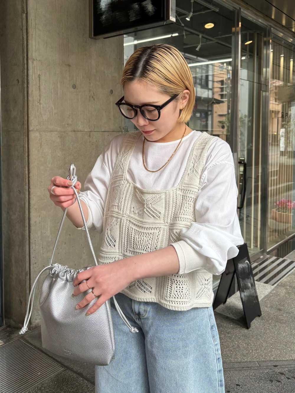 シルバー系のショルダーバッグ、ブルー系のデニムパンツ、ホワイト系のニット/セーターを着用したレディースの春コーディネートの4枚目の写真