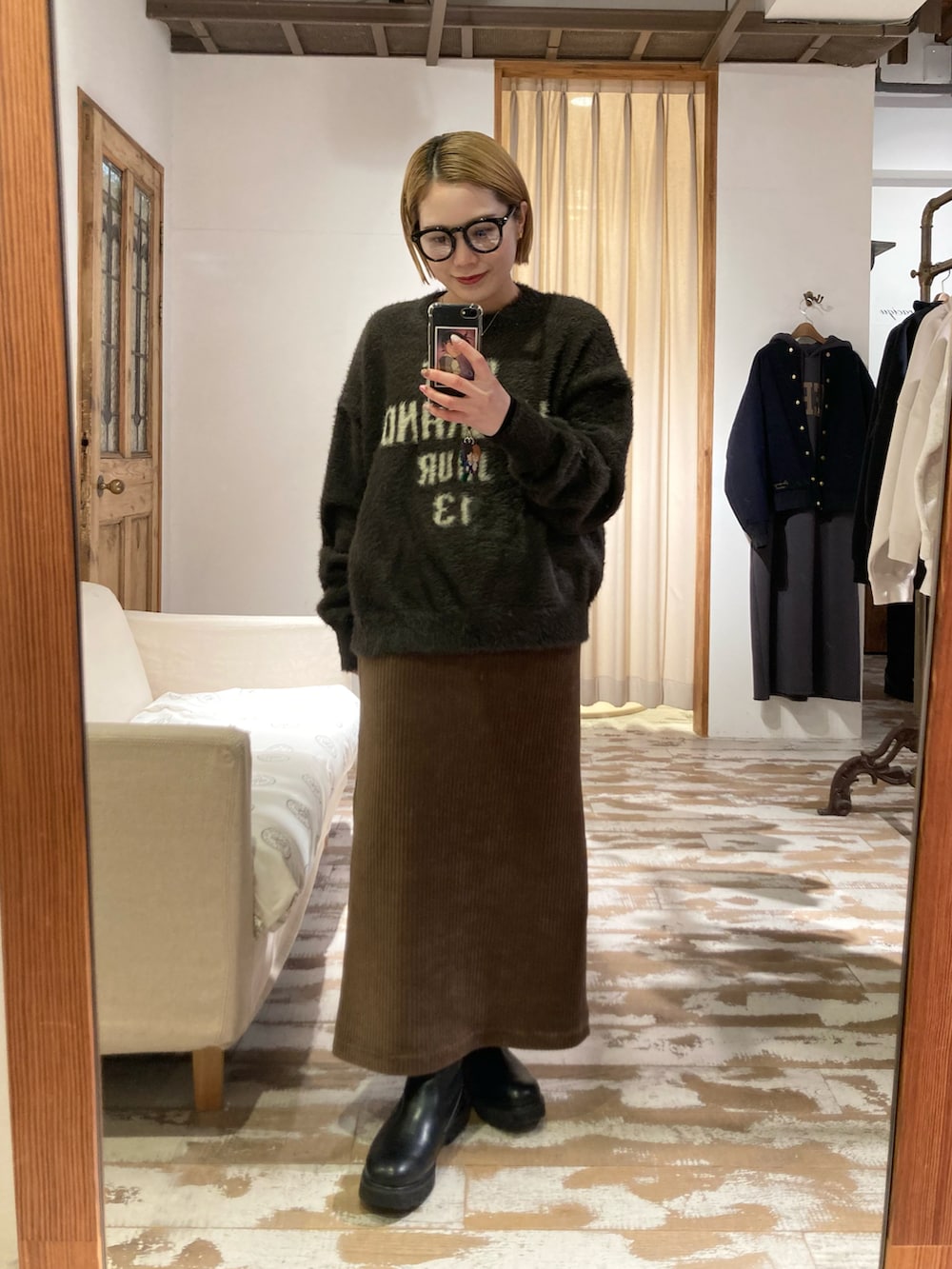 ブラック系のブーツ、ゴールド系のショルダーバッグ、ブラウン系のスカートを着用したレディースの冬コーディネートの5枚目の写真