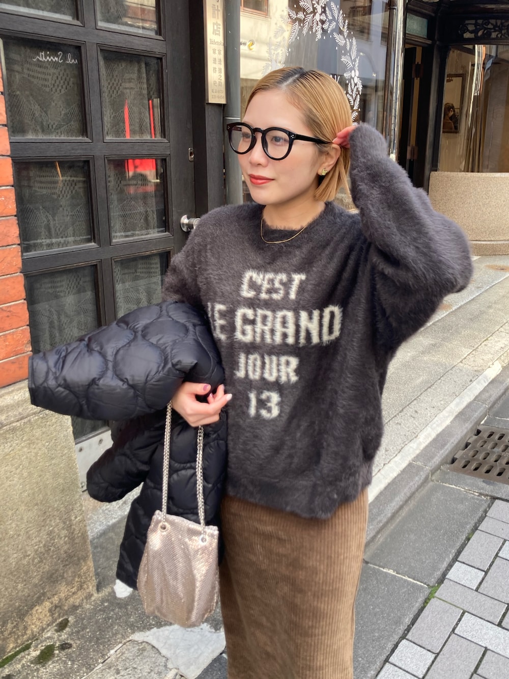 ブラック系のブーツ、ゴールド系のショルダーバッグ、ブラウン系のスカートを着用したレディースの冬コーディネートの3枚目の写真