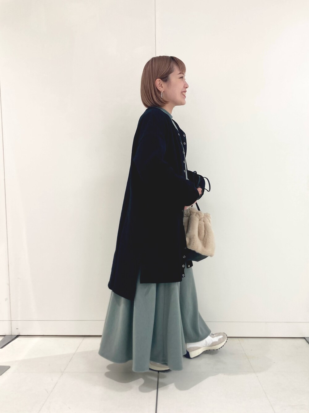 グリーン系のTシャツ/カットソー、グリーン系のスカート、ベージュ系のスニーカーを着用したレディースの秋コーディネートの3枚目の写真